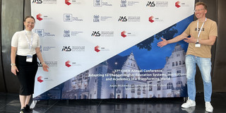 Olga Wagner (links) und Uwe Wilkesmann (rechts) stehen vor dem Poster der CHER Konferenz.